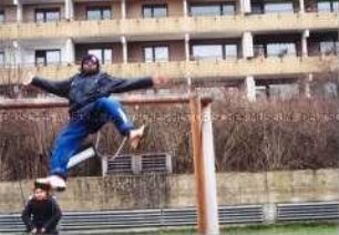 Von der Schaukel abspringender, dunkelhäutiger Junge (Altersgruppe 14-17)