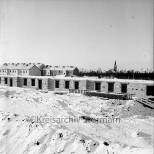 Waldschneise: vorne Baustelle von Wohngebäude, rechts dahinter der Friedhof Harksheide, links Wohngebäude des Stonsdorfer Weges, im Hintergrund die Kirche des kirchlichen Zentrums Harksheide und Wohngebäude der Falkenbergstraße: Blick nach Westen: Winterbild