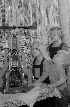 Drei Kinder vor einer Weihnachtspyramide