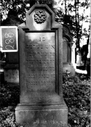Grabstein 288 (Index: 100112040) Material: Sandstein Zustand: gut Maße HxBxT: 132x45x16 cm Beschreibung: Stele, profilierter Sockel, Abschluß: Sonderform, rechteckiges Schriftfeld eingetieft Symbolik: Blüte: Grabstein 288