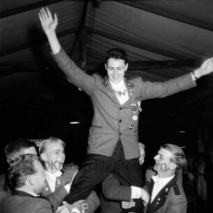 Schützenfest: Veranstalter Schützenverein Reinfeld und Umgebung von 1954 e.V.: Festplatz in der Ahrensböker Straße: im Festzelt: Königsproklamation: Jungschützenkönig Peter Claußen auf den Schultern seiner Schützenbrüder, grüßt mit erhobenen Armen: im Hintergrund Gäste, 2. September 1961