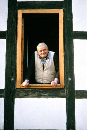Portrait eines älteren Herrn der aus dem Fenster schaut