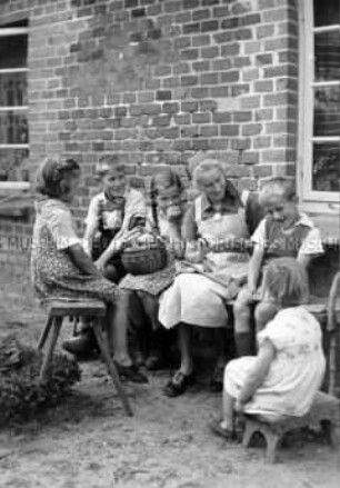 Arbeitsmaid des Reichsarbeitsdienstes bei Handarbeit und Kinderbetreuung, Klöhnen vor dem Haus