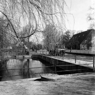 Dorfstraße: Feuerlöschteich mit Geländer: links Baum: rechts Lkw: dahinter Wohnhaus