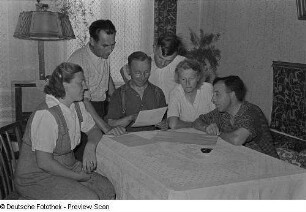 Alfred Glöckner (Mitte) spricht mit einigen Vorstandsmitgliedern der Hausgemeinschaft "Fortschritt" in Seehausen über den Plan der Jahresfeier; links (stehend) der Vorsitzende der Hausgemeinschaft, Paul Musy