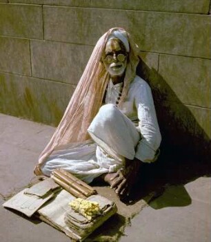 Schriftgelehrter, auf der Straße an eine Wand gelehnt sitzend : Kalkutta (Indien). Schriftgelehrter, auf der Straße an eine Wand gelehnt sitzend