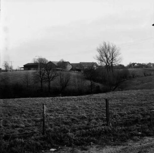 Blick über Knicklandschaft: im Vordergrund Zaun: im Hintergrund Bauern- und Wohnhäuser