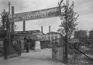 Industrie-Kraftwerk. Werktor mit Wachgebäude der Volkspolizei (Dienstzweig Betriebsschutz), davor ein Posten sowie ein Aufsteller zum Tag der Volkspolizei, über dem Tor Transparent mit Losung "Die Volkspolizei - ein Freund und Helfer aller Werktätigen!" : Lauta (Niederlausitz). Industrie-Kraftwerk. Werktor mit Wachgebäude der Volkspolizei (Dienstzweig Betriebsschutz), davor ein Posten sowie ein Aufsteller zum Tag der Volkspolizei, über dem Tor Transparent mit Losung "Die Volkspolizei - ein Freund und Helfer aller Werktätigen!"