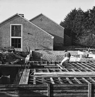 Volksschule: Soltausredder: Erweiterungsanbau: vorn Grundmauern und Holzverschalungen: darauf Arbeiter: links Baumaterial: dahinter Schulgebäude: hinten rechts Bäume