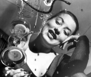 Silvester 1954. Die Frau des Fotografen trinkt genießerisch einen Cocktail. Fotografiert durch einen Glastisch