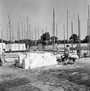 Bauhof: Glindfelder Weg: Aufenthaltsgebäude und Garagen in Bau: Fundamente und Mauerwerk, Gerüst, Arbeiter, mit Schubkarre, Stapel mit Mauersteinen: im Hintergrund Baukran
