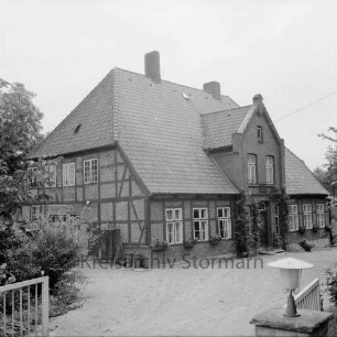Pastorat: Matthias-Claudius-Straße: Matthias-Claudius-Geburtsstätte (Nachfolgebau von Geburtshaus des Dichters Matthias Claudius): über Eingangstür Gedenktafel: im Vordergrund Einfahrt mit geöffnetem Tor, Lampe