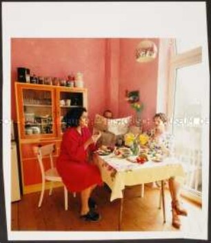 Menschen beim Frühstück in einer rosafarbenen Küche (Sonderthema: Guten Morgen)
