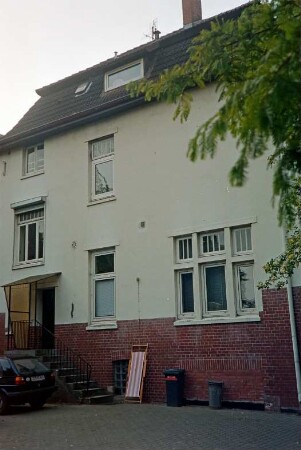 Kurparkallee 2: Stadtvilla: Rückseite, Teilansicht: Fenster, Tür mit vorgebautem Windfang, Treppe: Mansarddach: davor Parkplatz