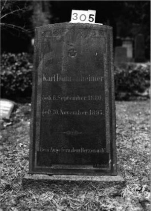 Grabstein 305 (Index: 100092673) Material: Granit Zustand: gut Maße HxBxT: 114x54x22 cm Beschreibung: aufgesockelte Stele, Segmentbogenabschluß, erhabenes Schriftfeld Symbolik: Stern Steinmetz: J. Bechtel: Grabstein 305