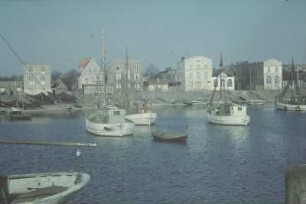 Reisefotos. Ortsteilansicht mit Fischerbooten. Am Ufer zum Trocknen ausgebreitete Fischernetze (vielleicht in Holland)
