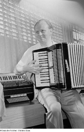 Ein Mann bedient ein Akkordeon des VEB Klingenthaler Harmonikawerke, Marke "Weltmeister", auf der Leipziger Herbstmesse 1954