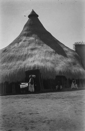 Eingang eines Gehöftes : Mann mit weißer Fahne vor dem Eingang des Gehöftes eines Oberhauptes in Ngaoundéré.