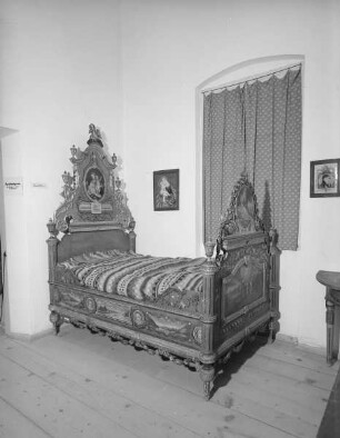 Bett mit vergoldeter Schnitzerei, Landschaftsdarstellungen und Heiligenbildern