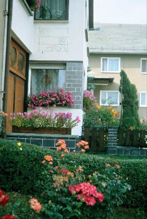 Blumen vor Haus, Vorbau mit Bild aus Metall