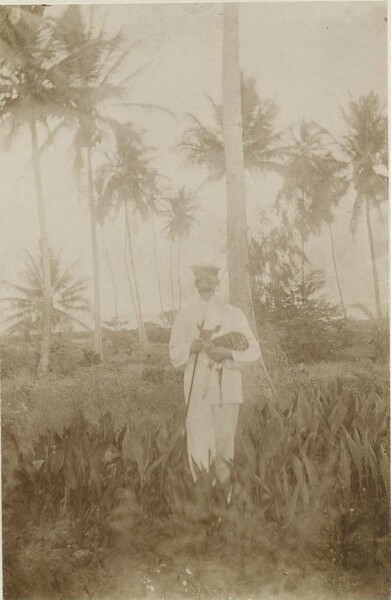 Officer in front of palm trees with baby gazelle