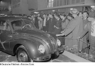 Besucher in einer Ausstellungshalle mit Fahrzeugen