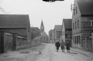 Gruppe auf Dorfstraße : Drei Personen auf einer Dorfstraße. Im Hintergrund eine Kirche