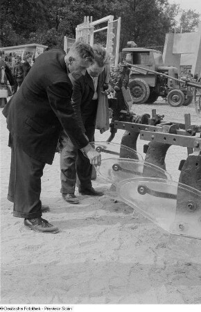 Ausstellungsbesucher an einem landwirtschaftlichen Gerät (Pflug)