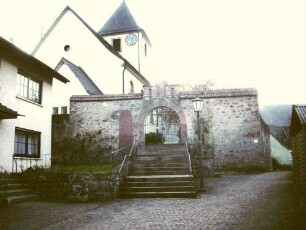 Ansicht von Westen mit Kirche (Kirchturm frühgotisch-Langhaus Barock erneuert) über Kirchhofmauer mit ehemaliger Toranlage (Wehrgang im 18 Jh abgetragen)