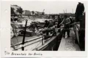 Brennholz wird aus Binnenschiffen entladen