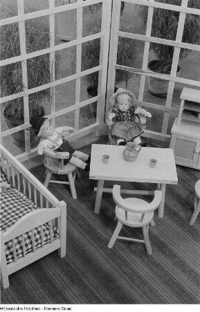 Zwei Puppen in einer möbilierten Puppenstube auf der Leipziger Herbstmesse 1954