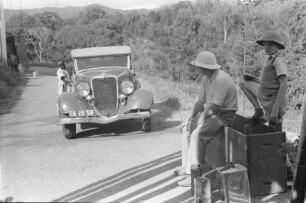 Autopflege : Ein Mann putzt ein Auto; zwei andere beobachten ihn dabei.