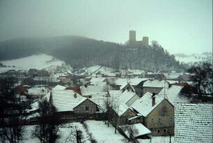 Blick über verschneite Dächer zur Burgruine