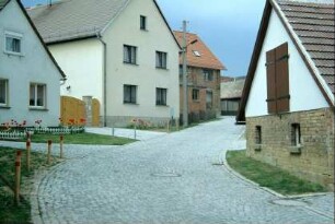 Blick entlang einer steil ansteigenden gepflasterten Dorfstraße