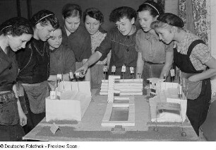 Eine Gruppe von Mädchen um ein Modell einer Sportanlage