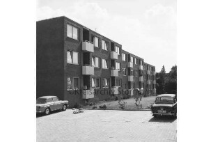 Wolkenweher Weg: Wohnblock der Gemeinnützigen Wohnstättengenossenschaft eG Bad Oldesloe: davor Grünanlage und Parkplatz mit Pkws