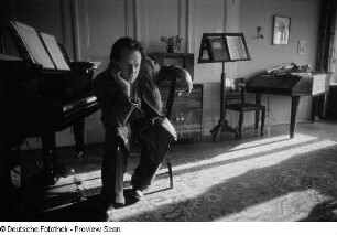Portrait Roger Rössings neben einem Klavier sitzend