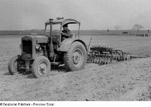 Bauer mit Traktor beim Pflügen eines Feldes