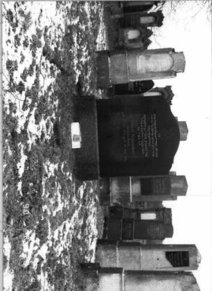Grabstein 5 (Index: 100114986) Material: polierter Granit und ? Zustand: sehr gut Maße HxBxT: 144x107x19 cm Beschreibung: Stele auf Sockel, mehrfach geschwungener Giebel mit Davidstern Symbolik: Davidstern: Grabstein 5
