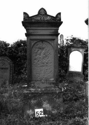 Grabstein 52 (Index: 99891683) Material: Sandstein Zustand: Inschrifttafel völlig zerstört Maße HxBxT: 159x55x25 cm Beschreibung: rechteckige Stele auf Sockel, großer Dachziegel: Palmette als Mittelakroter, zwei Eckakroterien Symbolik: Palmette im Mittelakroter, halbe Palmette in Eckakroterien: Grabstein 52