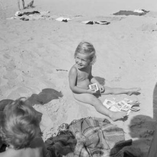 Nacktes Mädchen sitzt mit Spielkarten am Strand von Henkenhagen (heute: Ustronie Morskie)