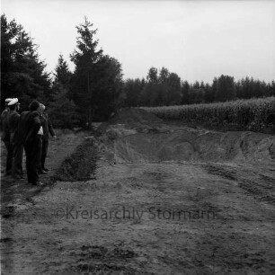 Forst bei Wilstedt: Abholzungsstopp und Abbaustopp von Kies durch Gemeinde und Polizei: rechts zwei Polizisten, ein Forstbeamter und ein weiterer Mann am Rand einer Kiesgrube bei der Begutachtung des Schadens: rechts und hinten Tannen: links Maisfeld