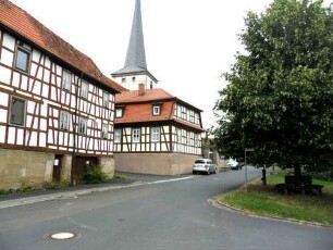 Ansicht von Südosten mit Kirche (über Kirchturmspitze) über Ortshäusern in Lage zu ebener Erde am Ortsrand