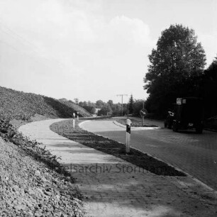 Straßenbau: Oldesloer Straße: Ausbau: Ortseingang mit Verkehrsinsel und Radfahrweg: rechts Trecker mit Pferdeanhänger: dahinter Bäume