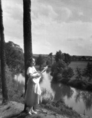 Junges Mädchen, am Ufer der Pegnitz stehend und zur Gitarre singend