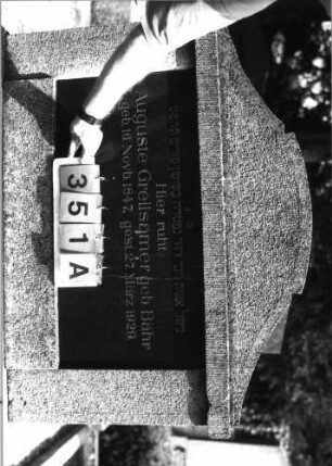 Grabstein 351 (Index: 99797202) Material: Kunststein, Granitplatte Zustand: gut Maße HxBxT: 137x114x22 cm Beschreibung: Stele, breit, getreppter Sockel, Konvexbogenaufsatz: Grabstein 351A