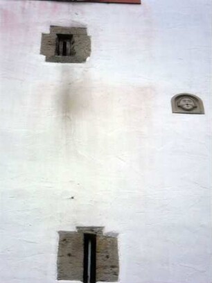 Kirchturm von Süden - Mittelgeschoß mit Schießscharten (Schlitzscharten) sowie Flachrelief (Kopf-renoviert) im Detail