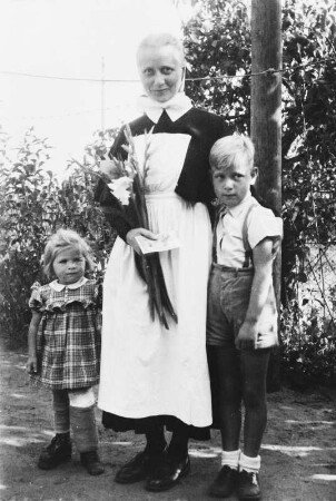 Diakonisse mit kleinem Mädchen mit Gipsbein und mit einem Jungen