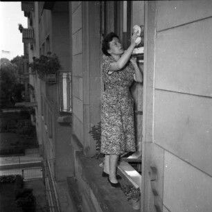 Hausfrauen leben gefährlich. Frau beim Fenster putzen, außen auf dem Sims stehend