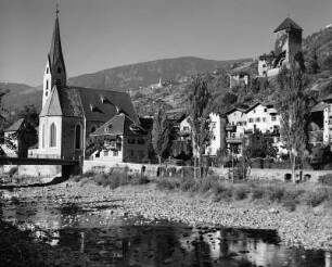 Klausen (Bozen). Stadtteilansicht über die Eisack mit Andreaskirche und Burg Branzoll